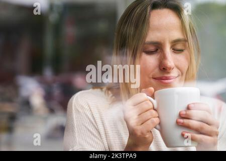 Portrait d'une femme aux yeux fermés, en appréciant une tasse de café Banque D'Images