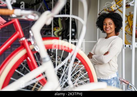Photo d'une femme afro-américaine qui se trouve dans son magasin avec ses vélos Banque D'Images