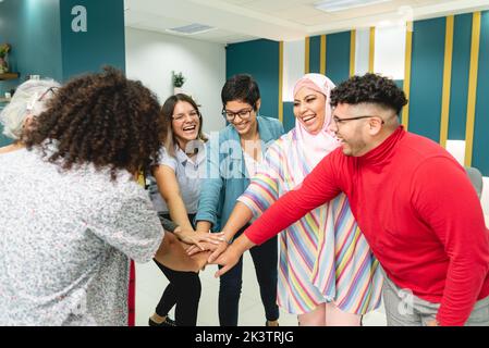 Groupe de collègues positifs et divers dans des vêtements à la mode debout dans le cercle et tenant les mains ensemble après la réunion au bureau au Costa Rica en plein jour Banque D'Images
