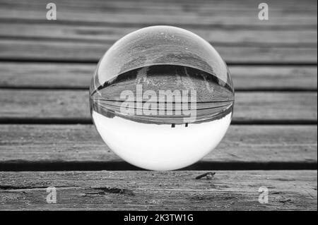 Boule de verre sur une jetée en bois sur un lac suédois au crépuscule en noir et blanc. Photo de la nature depuis la Scandinavie Banque D'Images