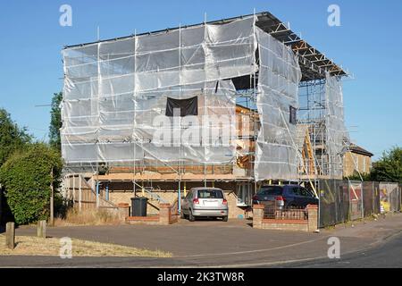 Construction de bâtiments en angle, conversion de bungalow en maison fermée en cocon plastique translucide et toit ondulé sur châssis d'échafaudage Royaume-Uni Banque D'Images