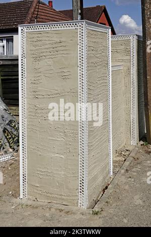 Gros plan bloc de béton mur limite avant grands jetées à nouveau construit bungalow maison montrant des perles d'angle en plastique blanc clouées sur rendu revêtement scratch UK Banque D'Images
