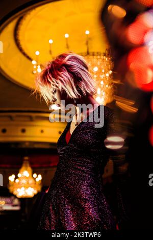 Vue latérale basse sur la femme dans une robe élégante dansant dans la salle éclairée à la fête Banque D'Images