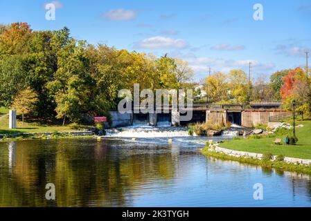 Vieux barrage en béton le long d'une rivière dans un centre-ville, le jour d'automne ensoleillé Banque D'Images