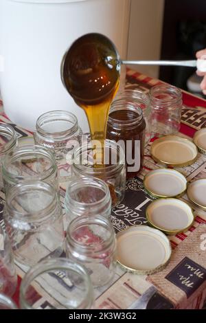 Remplissage de pots en verre de miel sur une table Banque D'Images