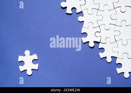 Pièces de puzzle à moitié assemblées et séparées. Vue de dessus, plat sur fond de papier blanc monochrome abstrait bleu. Copier-espace, placer pour le texte Banque D'Images