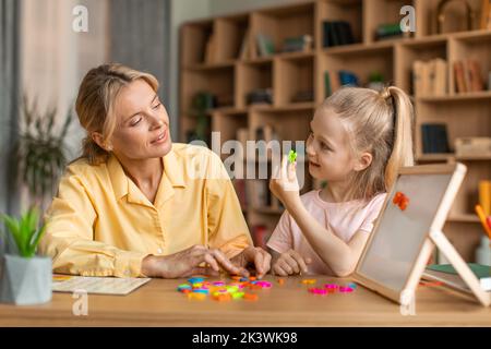 Classes de langue étrangère pour les enfants d'âge préscolaire. Jolie petite fille intelligente apprenant l'alphabet, prononçant et faisant des mots Banque D'Images