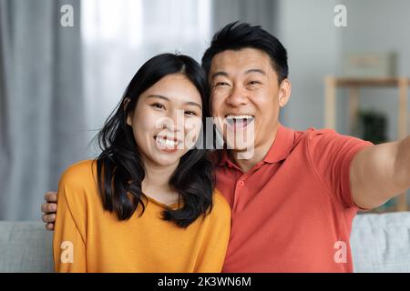 Portrait d'un couple asiatique joyeux qui prend le selfie à la maison Banque D'Images