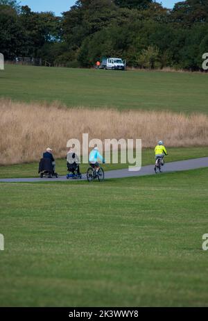 Deux hommes âgés sur des scooters de mobilité sont passés par des cyclistes sur la piste cyclable hors route de Bridlington à Sewerby dans le Yorkshire, en Angleterre Banque D'Images