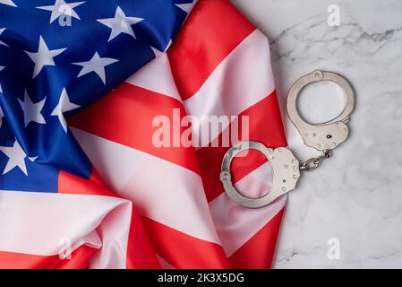 Papier peint avec le drapeau des états-unis à côté des menottes sur une base en marbre blanc. Système judiciaire américain Banque D'Images