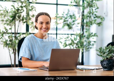 Portrait d'une belle femme d'affaires. Positif réussi latino ou brésilien jeune femme, directeur de la compagnie, entrepreneur, assis à un bureau dans un bureau moderne, regardant la caméra, souriant Banque D'Images