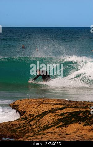 Une photo verticale d'un surfeur dans la mer à l'extrémité nord de Maroubra Beach, Sydney, Australie Banque D'Images