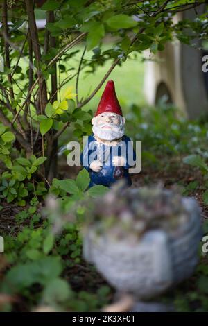 Une photo verticale d'un gnome de jardin parmi les feuilles vertes Banque D'Images