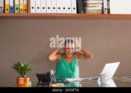C’est là. Une femme se jetant les mains par surprise tout en étant assise à son bureau. Banque D'Images