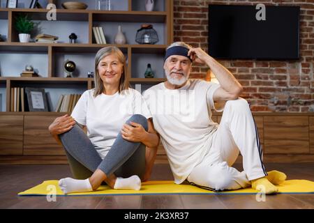 Heureux à cheveux gris mature couple âgé faisant de la gymnastique ensemble à la maison. Un mode de vie actif et sain pour les retraités. Fitness, loisirs, bien Banque D'Images