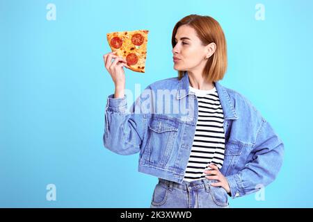 jeune femme avec tranche de pizza sur fond jaune. Banque D'Images