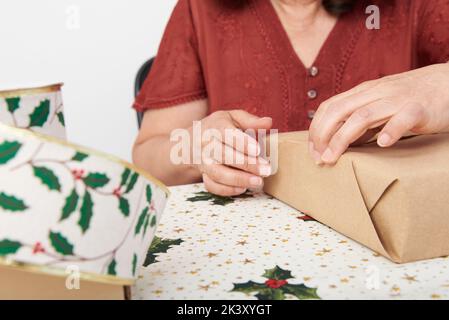 Femme adulte non reconnaissable emballant des cadeaux de Noël. Design lumineux avec espace de copie. Banque D'Images