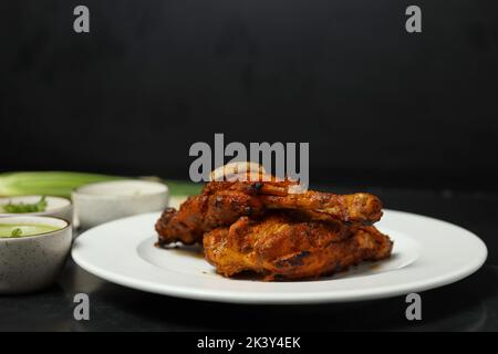 Les cuisses de poulet rôties croustillantes avec la peau brun doré avec des feuilles de thym vert sur blanc sur plaque en bois sombre, vue d'en haut Banque D'Images