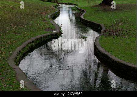 Un ruisseau a été contenu par des côtés en béton pour traverser un parc public Banque D'Images
