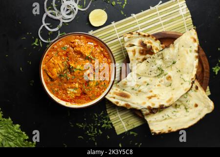 Masala de beurre de paneer servi avec du pain naan, des rondelles d'oignon et du citron, sur un fond noir avec espace pour le texte, curry indien Banque D'Images