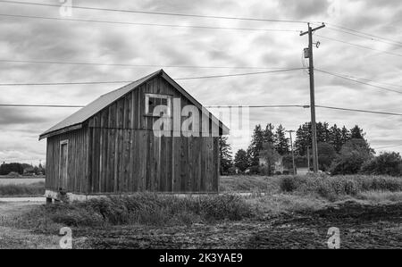 Ancienne ferme en bois dans la campagne au coucher du soleil avec nuages de tempête dans le ciel. Il y a un petit pré d'herbe autour de la maison. Personne, photo de voyage, Banque D'Images