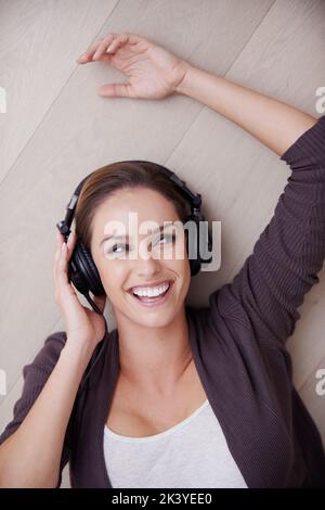 Ressentez le rythme. Une jeune femme souriant en écoutant de la musique sur son casque. Banque D'Images