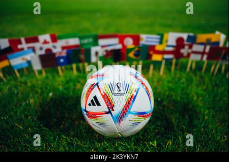 QATAR, DOHA, 18 JUILLET 2022 : coupe du monde de la FIFA, Qatar 2022. Ballon officiel Adidas sur l'herbe verte et les drapeaux nationaux des 32 participants. Banque D'Images