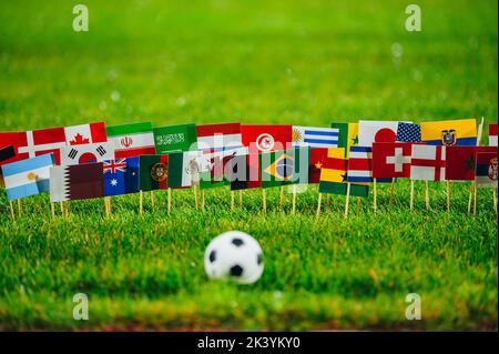 Ballon de football sur herbe verte et les 32 drapeaux nationaux. Papier peint pour tournoi de football Banque D'Images