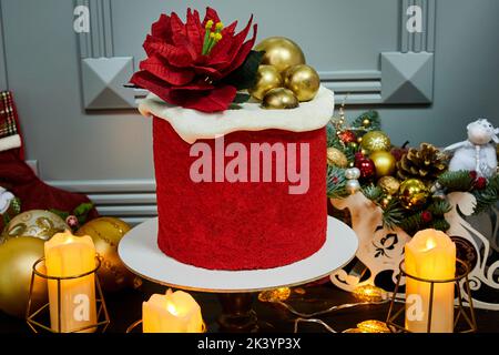 Gâteau de Noël rouge fait de gâteaux au miel, pruneaux et noix sur fond de bougies, guirlandes, branches de sapin et cônes Banque D'Images