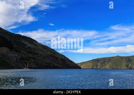 Le port d'Akaroa est situé à l'embouchure de l'île du Sud de la Nouvelle-Zélande. Un voilier est visible à gauche Banque D'Images