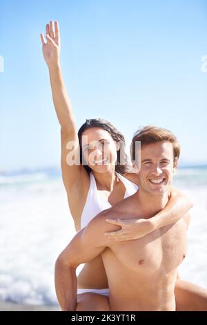 Romantisme et amusement sous le soleil. Un jeune couple charmant s'amusant sur la plage en été. Banque D'Images