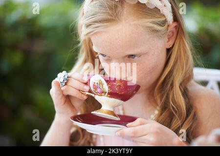 Siroter son thé comme une dame. Une petite fille mignonne ayant une fête de thé à l'extérieur. Banque D'Images