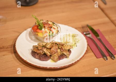 Le cou de porc est recouvert de champignons sautés, de pommes de terre en quartiers au romarin et de germe de blé. Banque D'Images