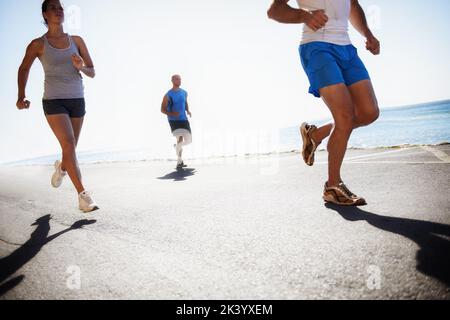 Courir est un mode de vie. Vue à angle bas d'un coureur à côté de l'océan. Banque D'Images