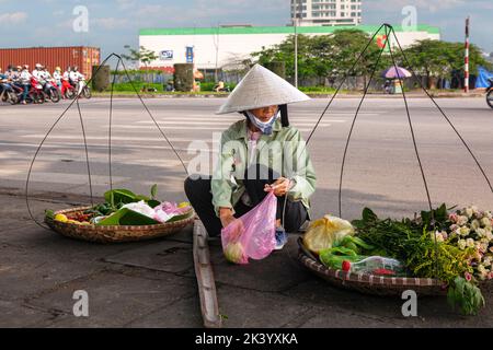 Un motard vietnamien portant un chapeau de bambou vendant de la nourriture de pannier dans la rue, Hai Phong, Vietnam Banque D'Images