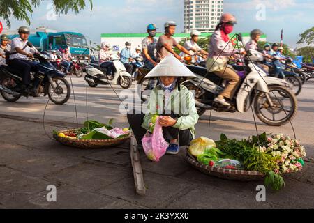 Un motard vietnamien portant un chapeau de bambou vendant de la nourriture de pannier dans la rue, Hai Phong, Vietnam Banque D'Images