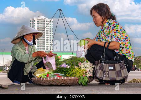 Un motard vietnamien portant un chapeau de bambou vendant de la nourriture de pannier dans la rue, Hai Phong, Vietnam Banque D'Images