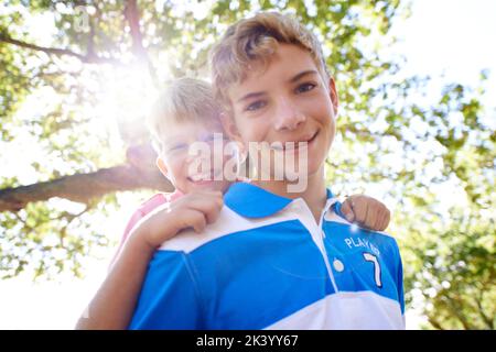 Vacances avec mon petit frère. Portrait d'un frère à angle bas donnant à sa jeune sœur un porcgyback. Banque D'Images