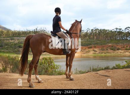 Découverte de la nature à cheval. Une jeune femme qui va faire un tour sur son cheval de châtaignier. Banque D'Images