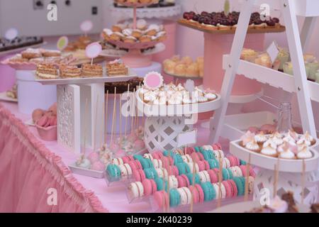 Plateaux avec macarons et meringue, dans un décor rose. Barre de bonbons Banque D'Images