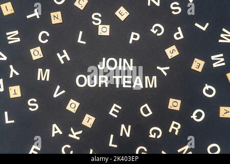 JOIGNEZ-VOUS À NOTRE MOT D'ÉQUIPE écrit sur fond de papier foncé. JOIGNEZ-VOUS À NOTRE TEXTE D'ÉQUIPE sur l'obscurité pour vos conceptions, concept. Banque D'Images