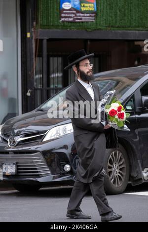 La veille de Rosh Hashana, le nouvel an juif, un homme orthodoxe rentre chez lui avec des fleurs. À Williamsburg, Brooklyn, New York. Banque D'Images