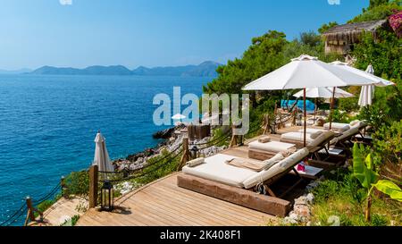 Chaises de plage avec parasols blancs donnant sur l'océan en Turquie pendant une journée d'été, lits de plage sur des rochers donnant sur l'océan Banque D'Images