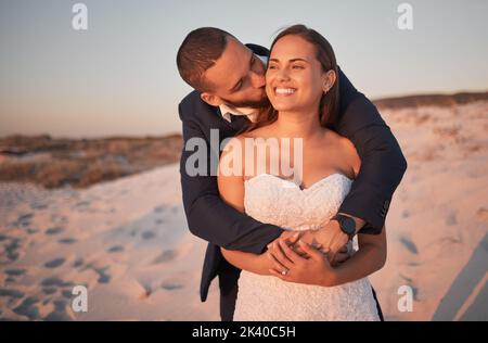 Mariage, couple et amour de la plage avec une mariée embrassante et marié sur la plage au coucher du soleil après une cérémonie ou une célébration. Heureux, baiser et le mariage avec un Banque D'Images