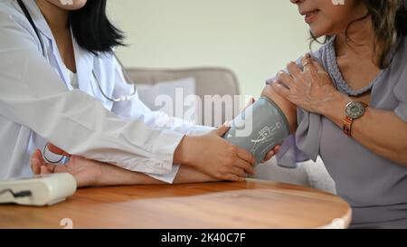 Une jeune femme asiatique professionnelle qui vérifie la tension artérielle et la fréquence cardiaque du patient à l'aide d'un moniteur de tension artérielle. Image rognée Banque D'Images