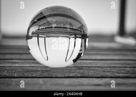 Boule de verre sur une jetée en bois sur un lac suédois au crépuscule en noir et blanc. Photo de la nature depuis la Scandinavie Banque D'Images