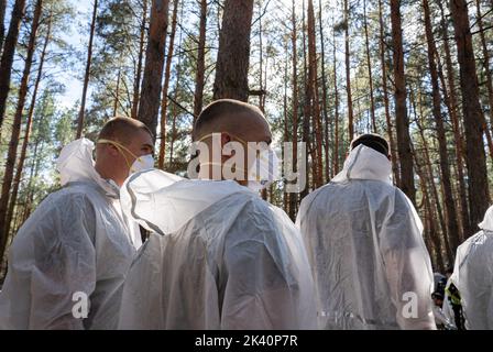 Les investigateurs sont vus porter des masques et des équipements de protection pendant l'exhumation. Un site de sépulture de masse a été trouvé dans la périphérie de la ville ukrainienne orientale, Izyum, région de Kharkiv, qui a été libérée de l'occupation russe il y a deux semaines. Au moins 445 nouvelles tombes ont été trouvées sur le site d'un cimetière existant alors que beaucoup n'ont que des numéros écrits sur la croix en bois. Tous les corps seront exhumés et envoyés pour examen médico-légal mais il a été dit lors des premières enquêtes que certains organes ont montré des signes de torture. Banque D'Images