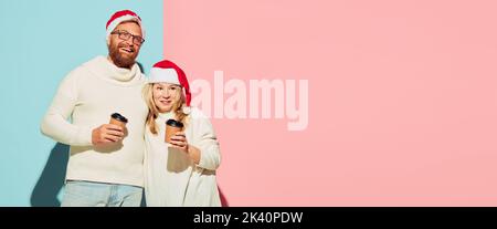 Jeune couple charmant portant des chapeaux de noël et des chandails chauds blancs goûtant du café. Concept romantique. Circulaire Banque D'Images