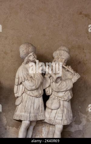 Une paire de musiciens jouant des cornetts de la sculpture collective du couronnement de Ferdinand I d'Aragon, dans la cour du Bargello, Florence. Banque D'Images