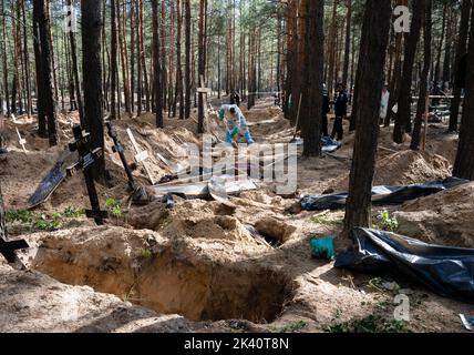 19 septembre 2022, Izyum, Ukraine: Un enquêteur portant un équipement de protection est vu exhuming corps avec des pelles. Un site de sépulture de masse a été trouvé dans la périphérie de la ville ukrainienne orientale, Izyum, région de Kharkiv, qui a été libérée de l'occupation russe il y a deux semaines. Au moins 445 nouvelles tombes ont été trouvées sur le site d'un cimetière existant alors que beaucoup n'ont que des numéros écrits sur la croix en bois. Tous les corps seront exhumés et envoyés pour examen médico-légal mais il a été dit lors des premières enquêtes que certains organes ont montré des signes de torture. (Credit image: © Ashley Chan/SOPA Images via ZUMA Banque D'Images